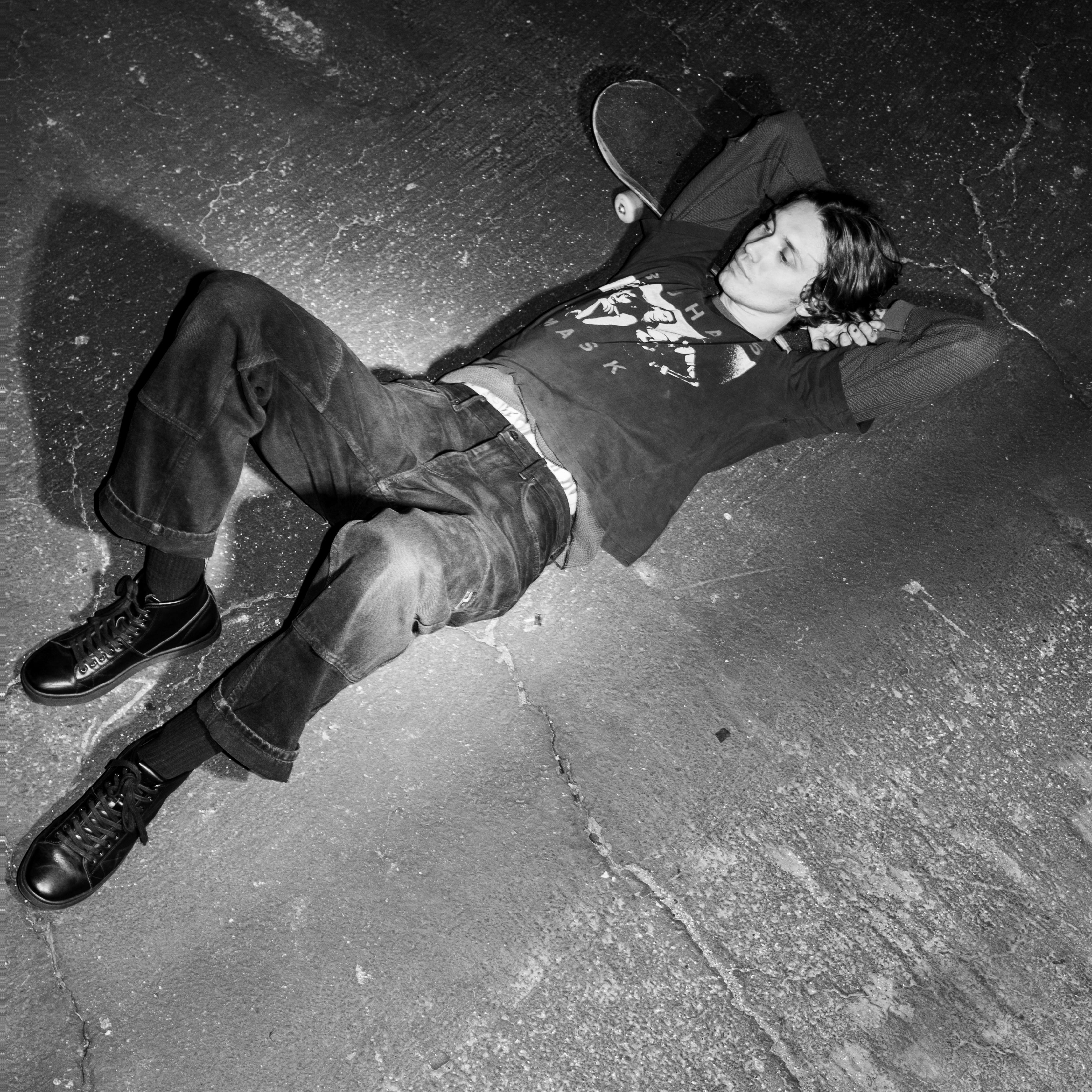 Lifestyle photo of a person lying on the pavement wearing FACT. CNTRL high-top shoes, showcasing the shoes' edgy style in a relaxed pose.