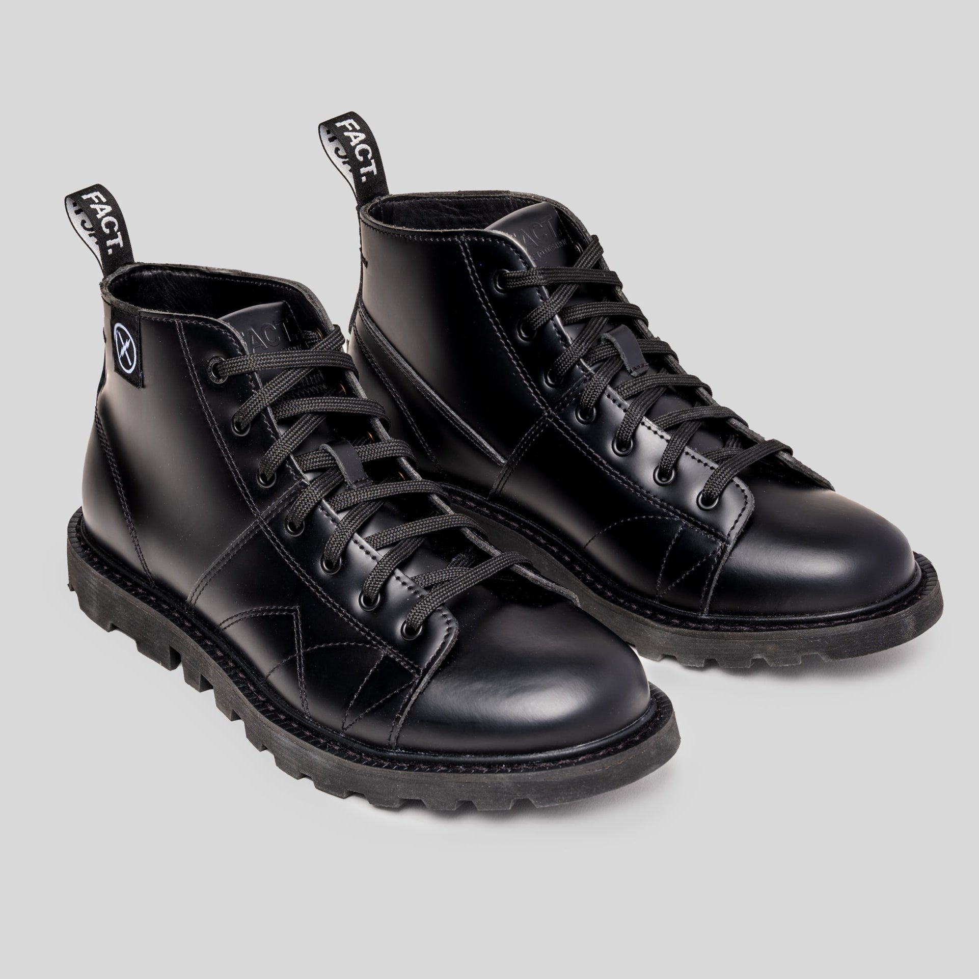 Pair of MNKY high-top black leather boots by FACT. with rectified leather upper, lugged tractor sole, and woven pull tabs.