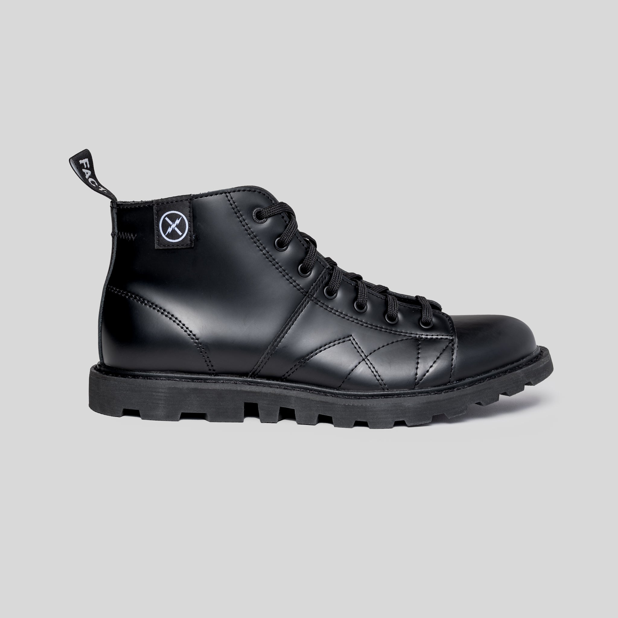 MNKY high-top black leather boot side view showing rectified leather upper, lugged sole, lace-up vamp, and FACT. logo pull tab.