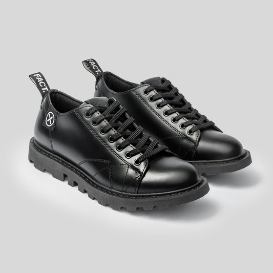 Pair of FACT. MNKY Shoes in black leather, photographed together on a studio surface.