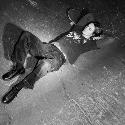 Lifestyle photo of a person lying on the pavement wearing FACT. CNTRL high-top shoes, showcasing the shoes' edgy style in a relaxed pose.