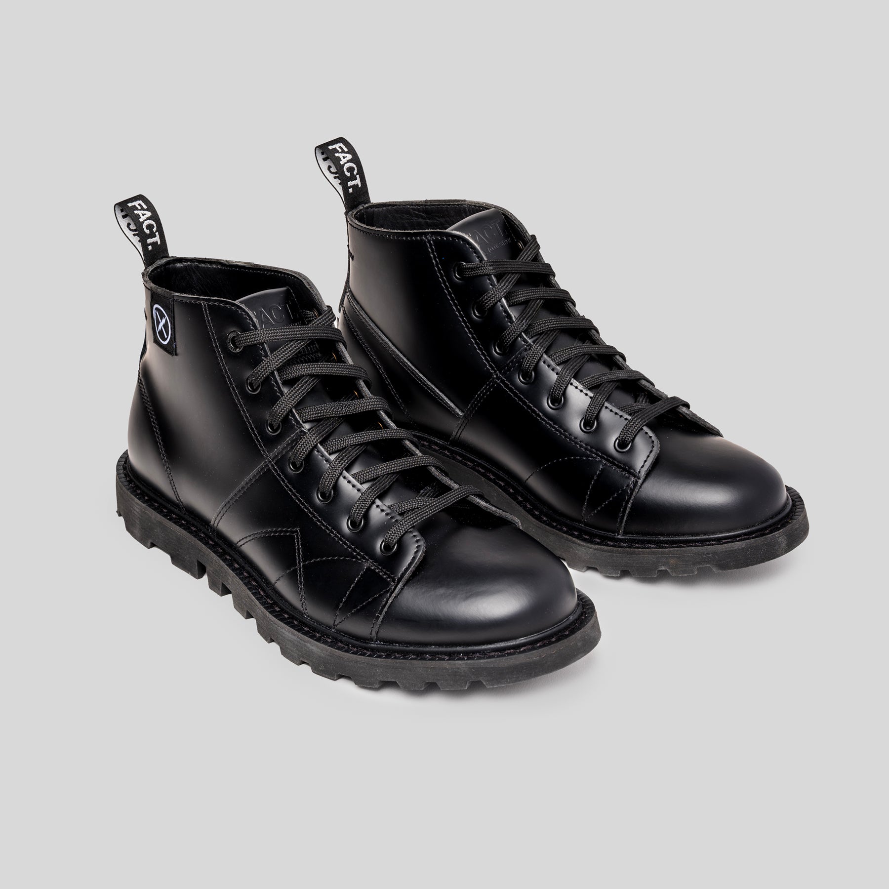 Pair of black leather monkey boots on a light gray background