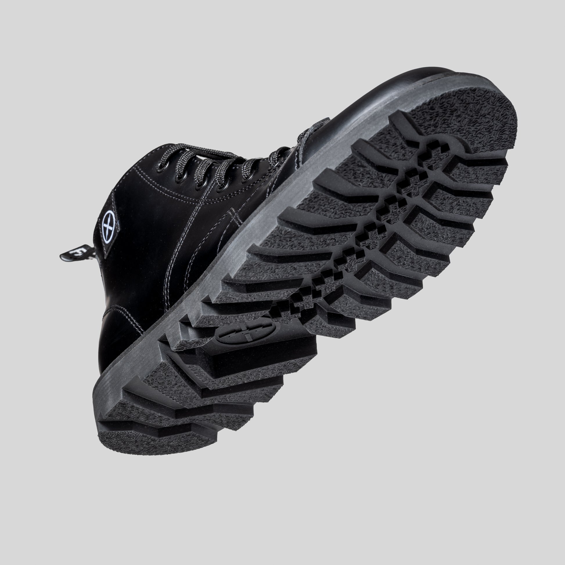 Close-up underside of the MNKY boot featuring its rugged, textured sole and black leather upper, captured on a light backdrop.